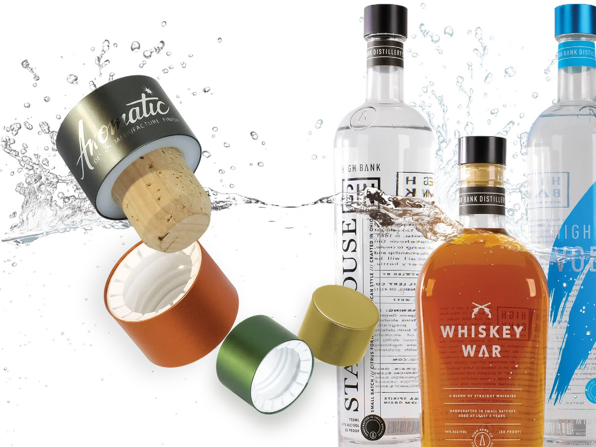 Anodized and metallized spirits caps in a splash of water beside gin, whiskey and vodka bottles